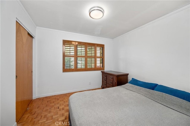 bedroom featuring a closet, ornamental molding, and light parquet flooring