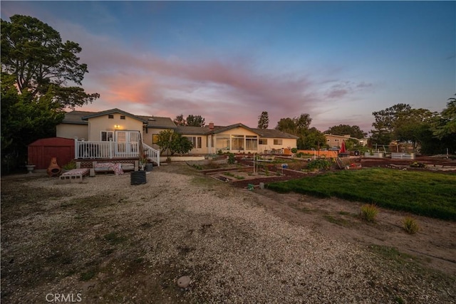 back house at dusk featuring a lawn and a wooden deck