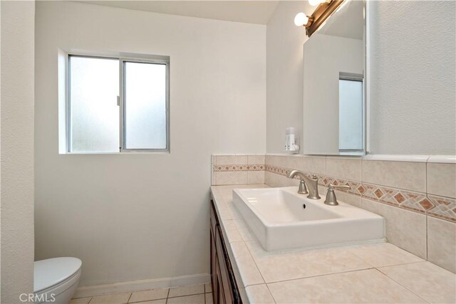 bathroom featuring toilet, sink, and tile patterned flooring