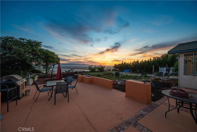 patio terrace at dusk featuring grilling area