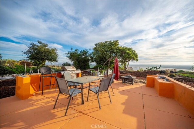 view of patio / terrace with a water view, a fire pit, and grilling area