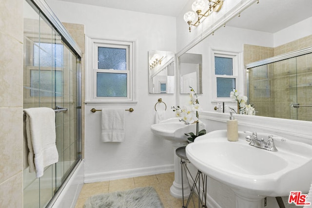 bathroom featuring bath / shower combo with glass door, a chandelier, tile patterned floors, and dual sinks