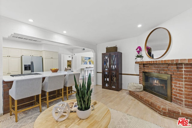 living room featuring a brick fireplace and light hardwood / wood-style floors