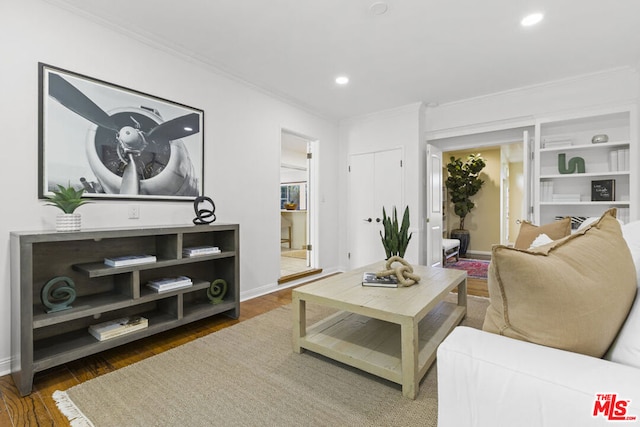 living room with built in shelves, dark hardwood / wood-style floors, and crown molding