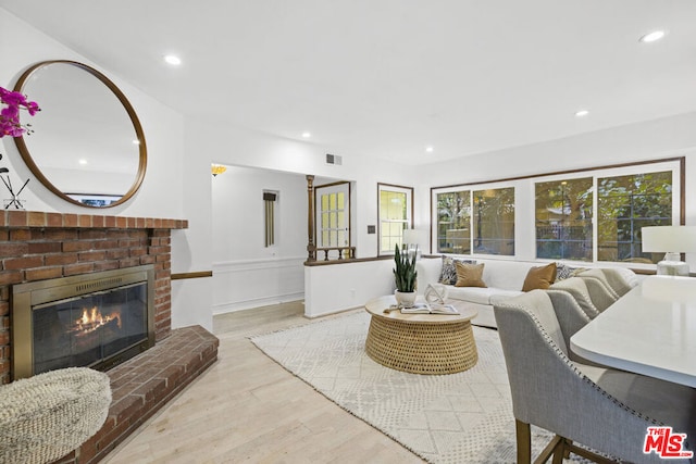 living room featuring a brick fireplace and light hardwood / wood-style flooring