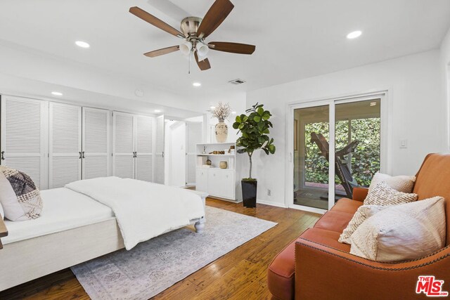 bedroom with ceiling fan, access to exterior, two closets, and dark hardwood / wood-style floors