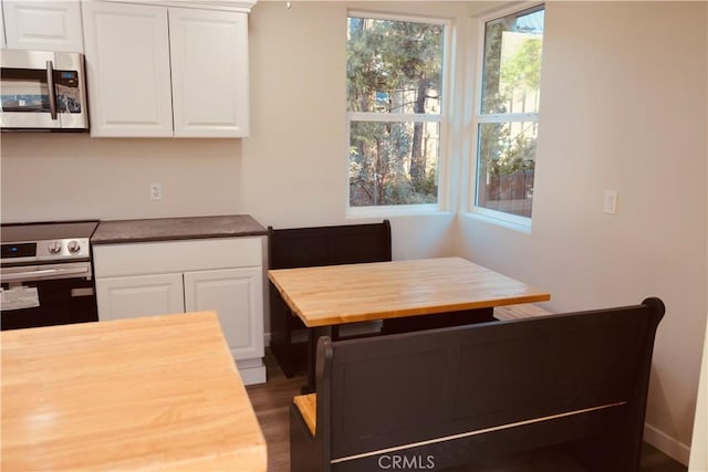 kitchen featuring dark wood-type flooring, stainless steel appliances, butcher block counters, and white cabinetry