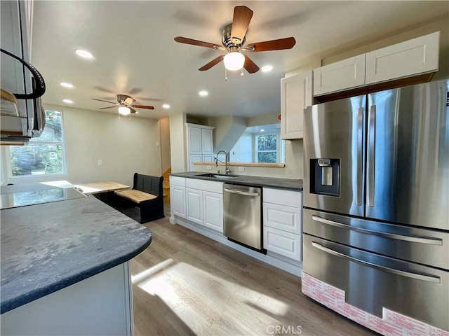 kitchen featuring ceiling fan, appliances with stainless steel finishes, light wood-type flooring, white cabinets, and sink