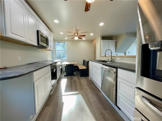 kitchen featuring ceiling fan, light hardwood / wood-style floors, sink, white cabinetry, and stainless steel appliances