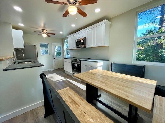 kitchen with dark hardwood / wood-style floors, sink, a healthy amount of sunlight, appliances with stainless steel finishes, and white cabinets