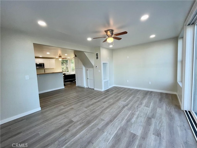 unfurnished living room featuring ceiling fan and hardwood / wood-style flooring