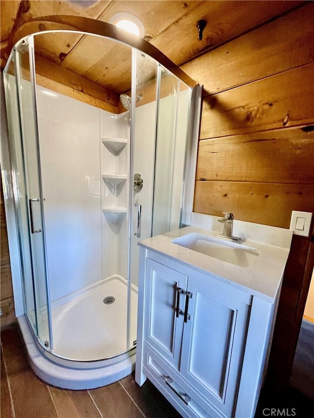 bathroom featuring a shower with shower door, wood walls, and vanity