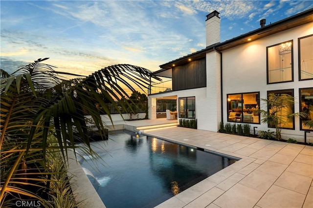 pool at dusk featuring a patio