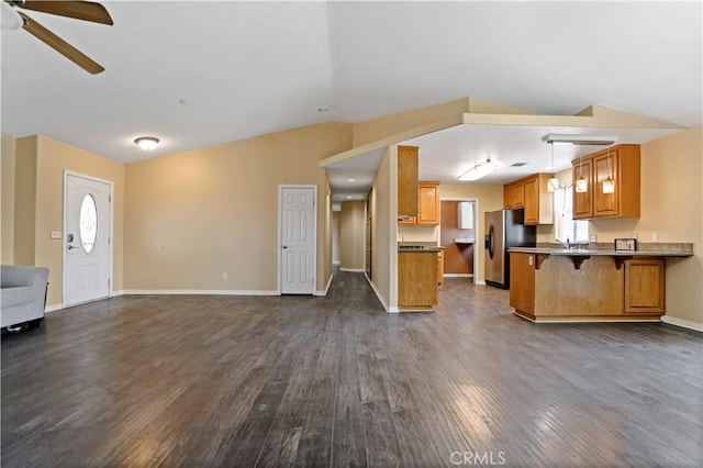 unfurnished living room featuring dark hardwood / wood-style flooring, vaulted ceiling, ceiling fan, and sink