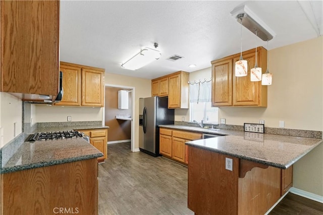 kitchen featuring sink, dark wood-type flooring, kitchen peninsula, decorative light fixtures, and appliances with stainless steel finishes