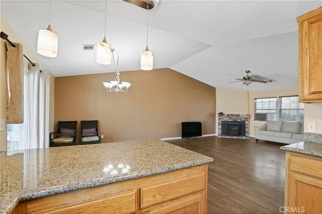 kitchen featuring light stone counters, decorative light fixtures, a fireplace, dark hardwood / wood-style floors, and lofted ceiling