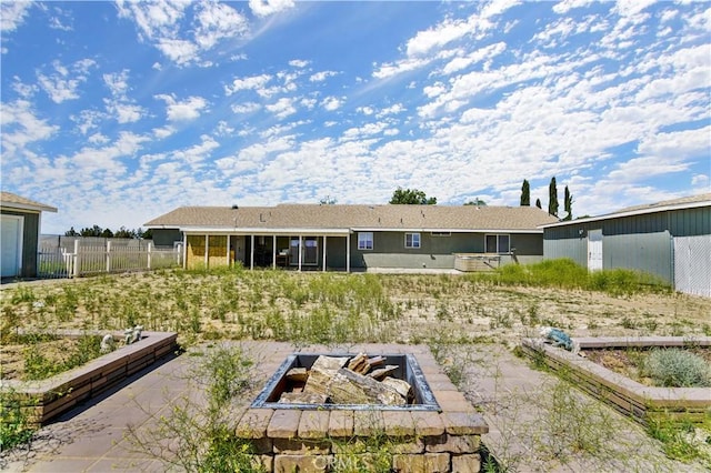 rear view of house featuring a fire pit and a sunroom