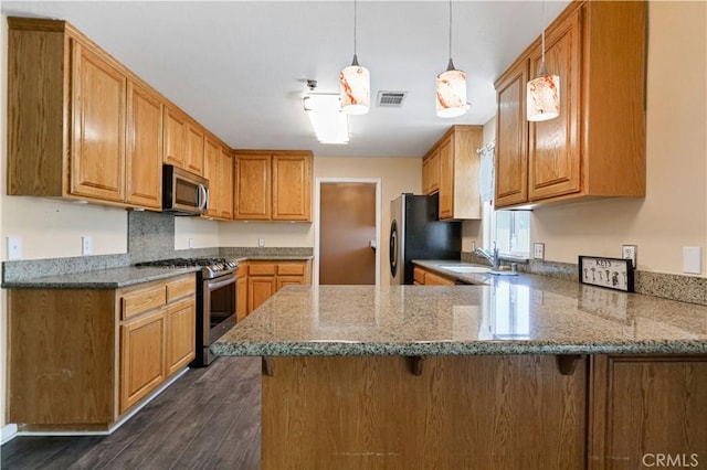 kitchen with light stone countertops, stainless steel appliances, dark hardwood / wood-style flooring, kitchen peninsula, and decorative light fixtures