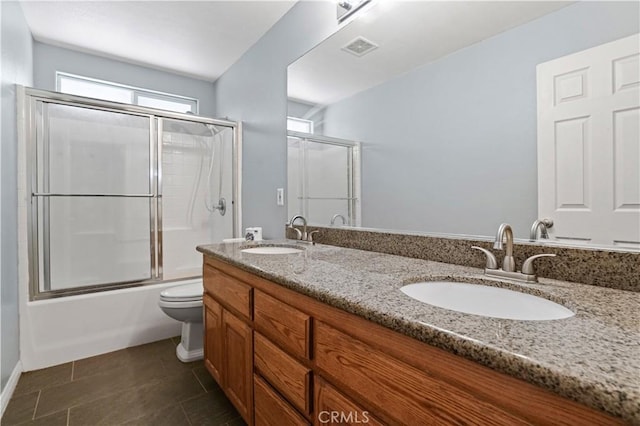 full bathroom with tile patterned floors, vanity, combined bath / shower with glass door, and toilet