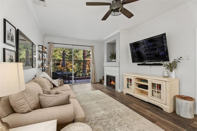 living room with dark hardwood / wood-style floors, ceiling fan, crown molding, and a tiled fireplace