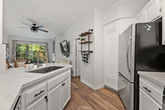 kitchen featuring stainless steel fridge, hardwood / wood-style flooring, white cabinetry, and ornamental molding