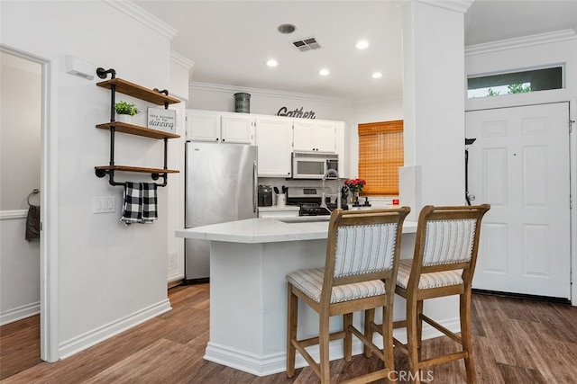 kitchen with crown molding, dark hardwood / wood-style flooring, white cabinetry, and stainless steel appliances