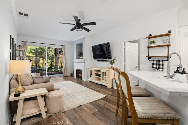 living room featuring crown molding, dark hardwood / wood-style flooring, ceiling fan, and sink