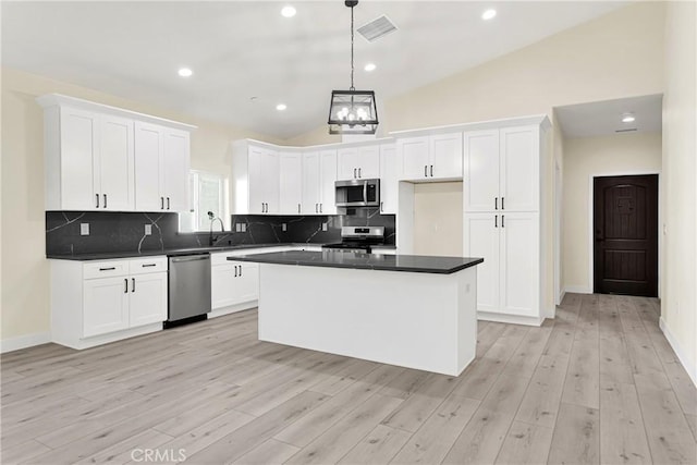 kitchen with white cabinets, a center island, stainless steel appliances, and vaulted ceiling