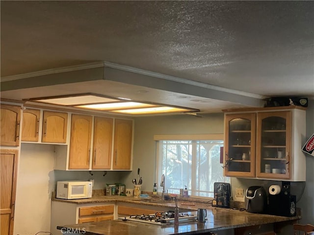 kitchen featuring dark stone countertops, ornamental molding, sink, and stainless steel gas cooktop