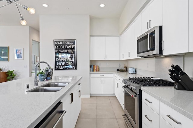 kitchen with light stone counters, sink, white cabinets, and stainless steel appliances