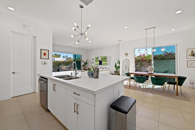 kitchen featuring hanging light fixtures, white cabinetry, sink, and a kitchen island with sink