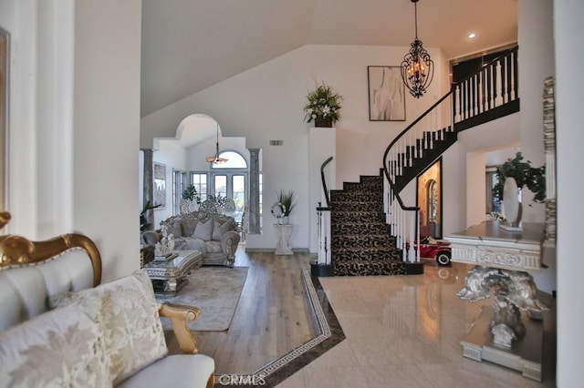 entryway with hardwood / wood-style floors, lofted ceiling, french doors, ornate columns, and a chandelier