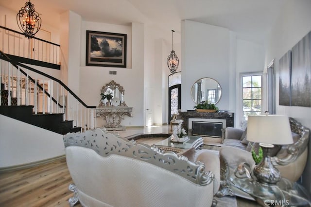 living room with a chandelier, high vaulted ceiling, and light hardwood / wood-style floors