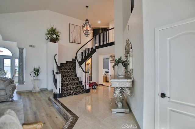 foyer featuring a chandelier, wood-type flooring, and high vaulted ceiling