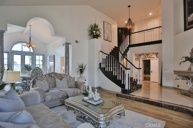 living room with hardwood / wood-style floors, high vaulted ceiling, and a chandelier