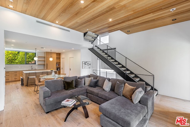 living room with light hardwood / wood-style floors, wooden ceiling, and sink