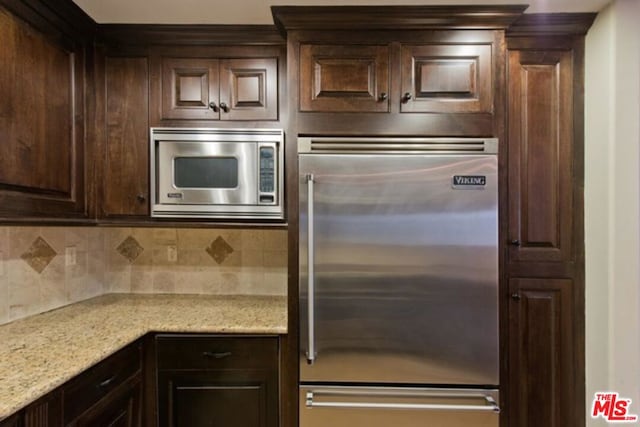 kitchen featuring light stone countertops, dark brown cabinets, stainless steel appliances, and tasteful backsplash