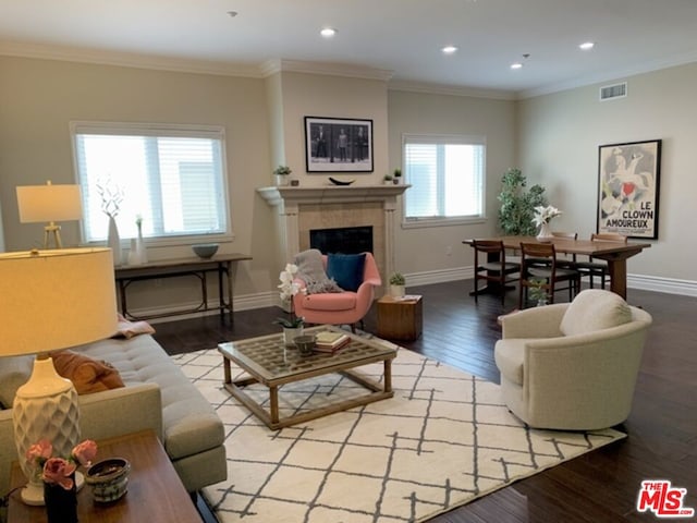 living room featuring light hardwood / wood-style floors, ornamental molding, and a tile fireplace