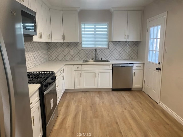 kitchen with backsplash, stainless steel appliances, sink, light hardwood / wood-style flooring, and white cabinetry