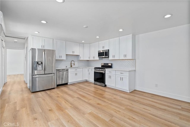 kitchen featuring sink, white cabinetry, tasteful backsplash, light hardwood / wood-style flooring, and appliances with stainless steel finishes