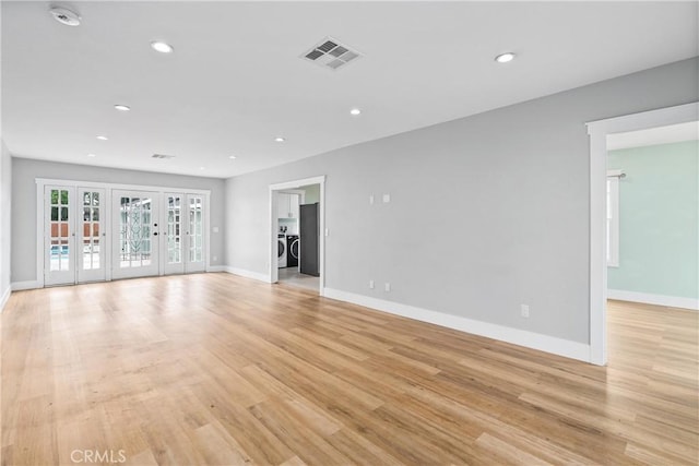 unfurnished living room with french doors, light wood-type flooring, and separate washer and dryer