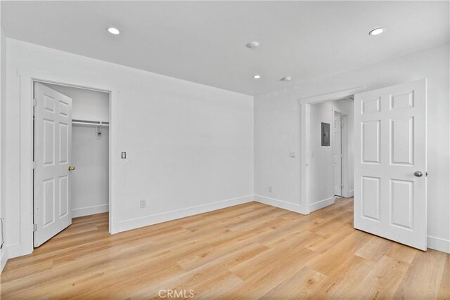 unfurnished bedroom featuring a walk in closet, light wood-type flooring, and a closet