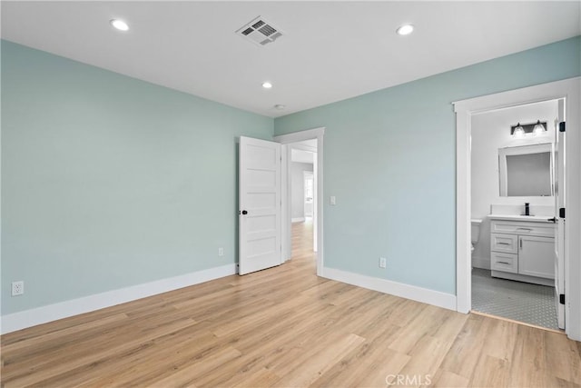 unfurnished bedroom featuring sink, light wood-type flooring, and ensuite bathroom