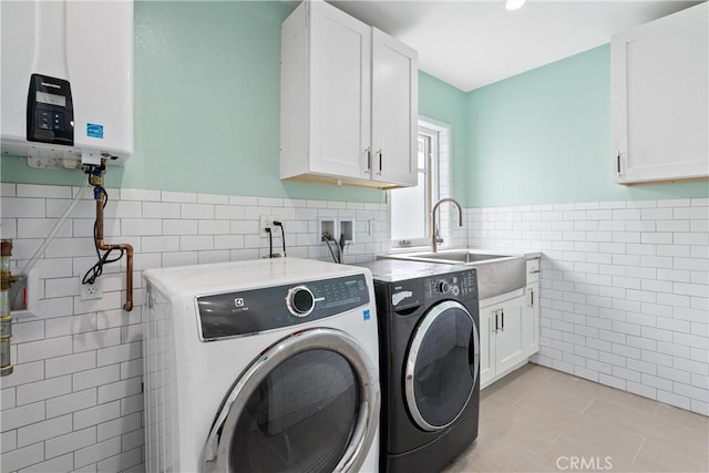 laundry room featuring cabinets, tankless water heater, sink, washer and clothes dryer, and light tile patterned flooring