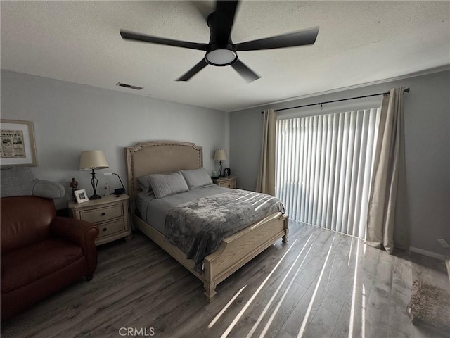 bedroom with a textured ceiling, dark hardwood / wood-style flooring, and ceiling fan