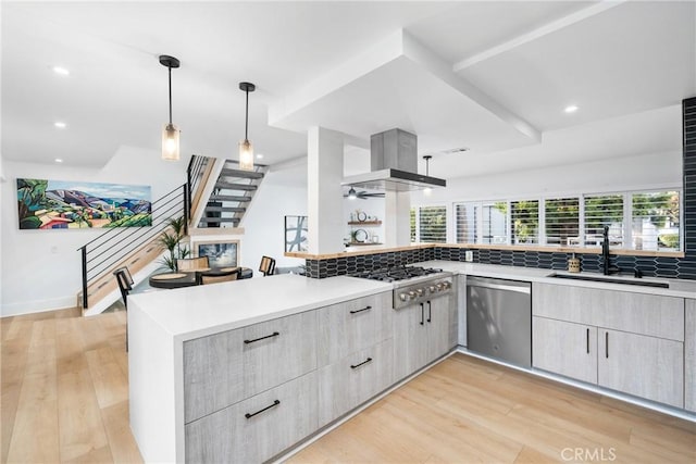 kitchen featuring kitchen peninsula, sink, stainless steel appliances, and exhaust hood