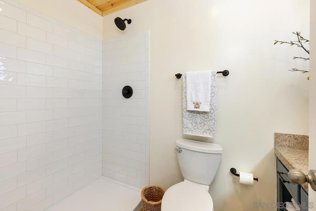 bathroom with tiled shower, vanity, and toilet