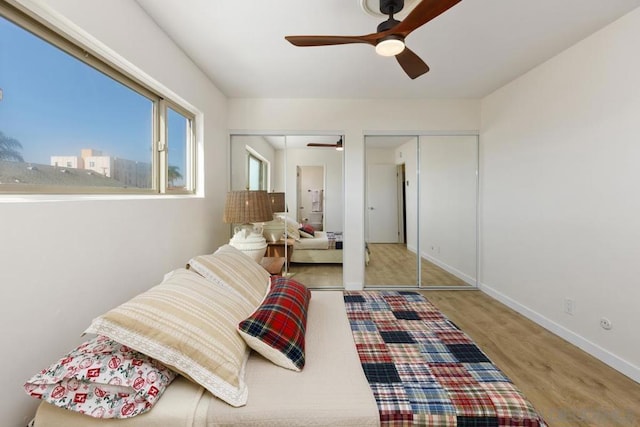 bedroom with ceiling fan, light hardwood / wood-style flooring, and two closets