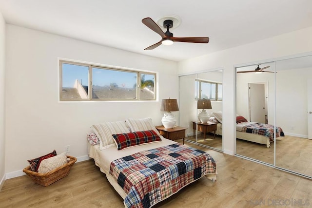 bedroom featuring hardwood / wood-style floors, ceiling fan, and multiple closets