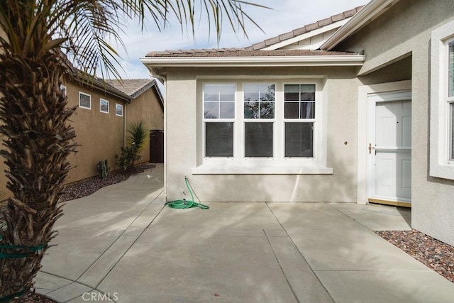 view of property exterior featuring a tile roof, a patio, and stucco siding